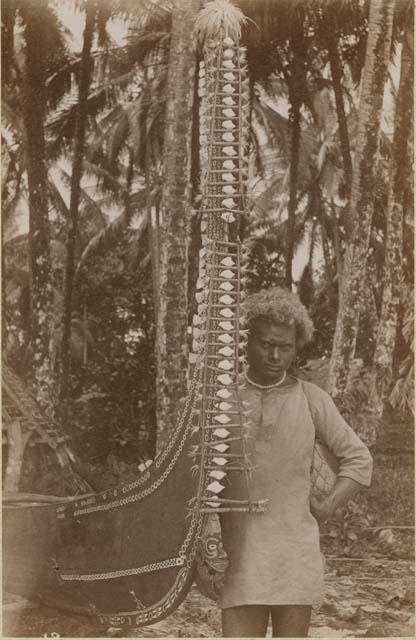 Person standing next to canoe decorated with shells