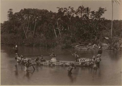 Men with spears in and around canoe