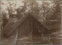 Youth standing by a thatched "A" frame structure