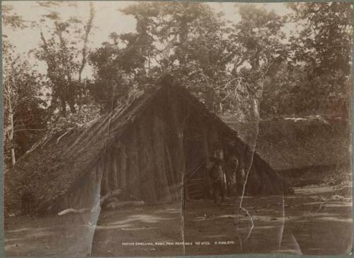 Youth standing by a thatched "A" frame structure