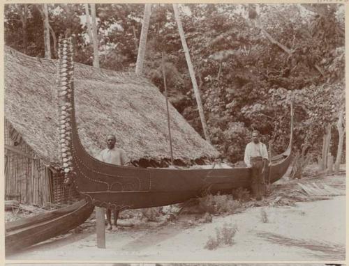 Two men with canoe on beach