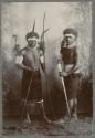 Studio portrait of two men, one with bow and arrow