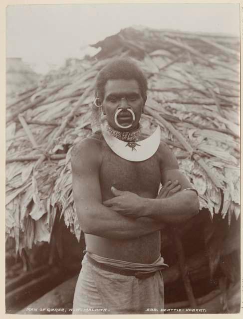 Man of Qarea standing in front of a house