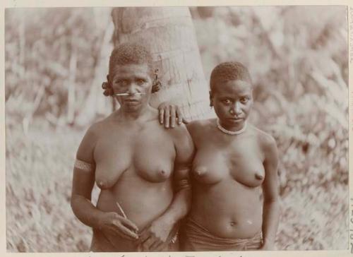 Two women standing in front of a tree