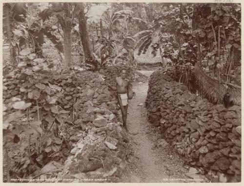 Man standing next to protective stone walls at Matema