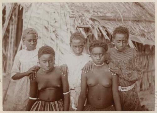 Group of girls in front of thatched structure