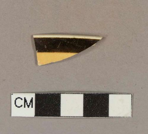 Brown and orange factory decorated whiteware rim sherd