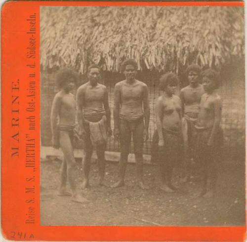 Group of people standing in front of thatched structure