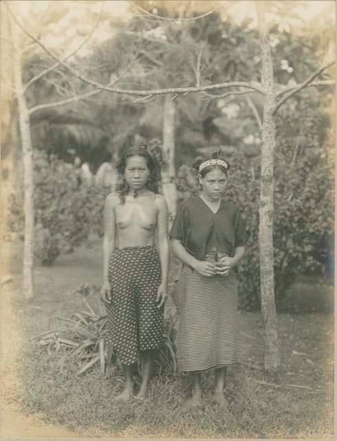 Two women standing in front of trees