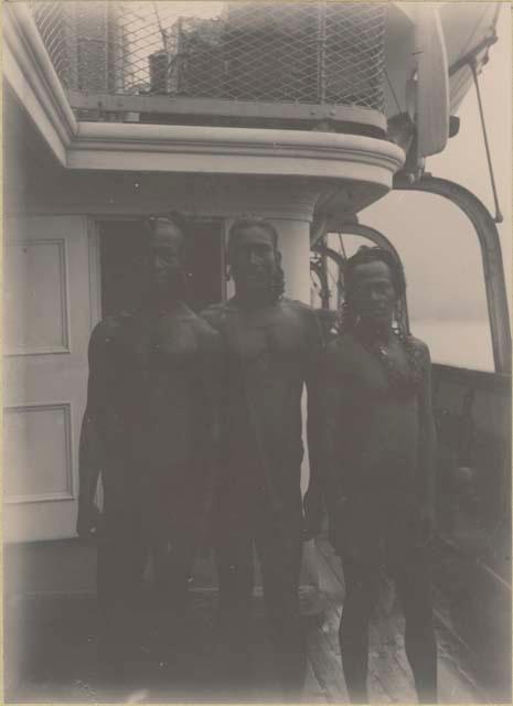 Three men standing on deck of ship