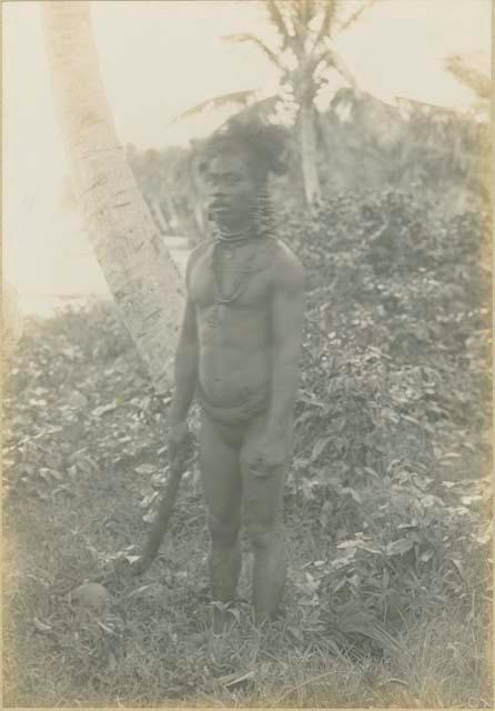 Man holding knife, standing next to skull