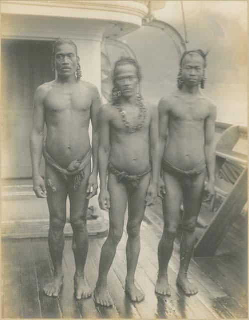 Three men standing on deck of ship