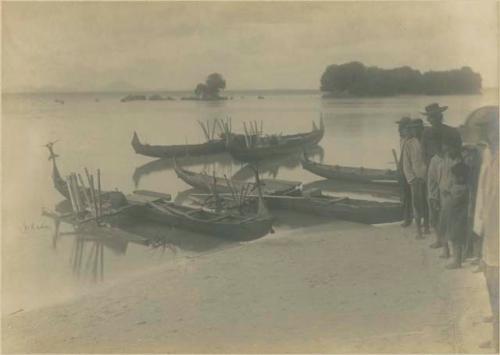 People and canoes along shore