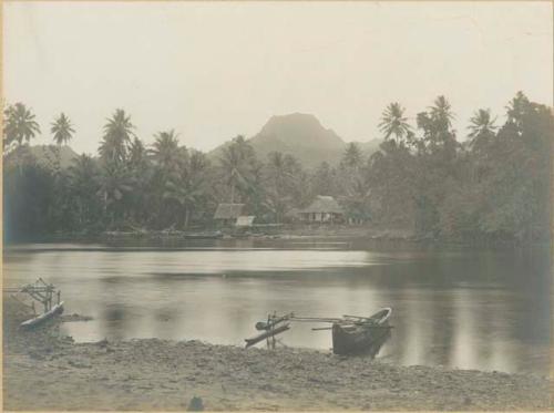 View of harbor shoreline at Port Lottin, Kosrae, including outrigger canoes and houses