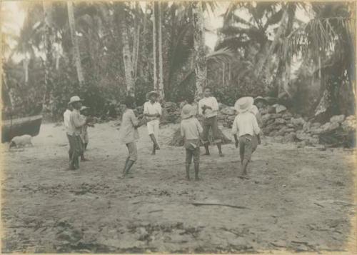 Group of boys, with pig and rock wall in background