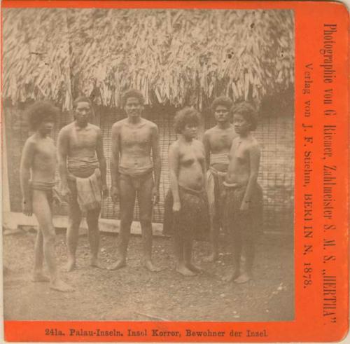 Group of people standing in front of a thatched structure