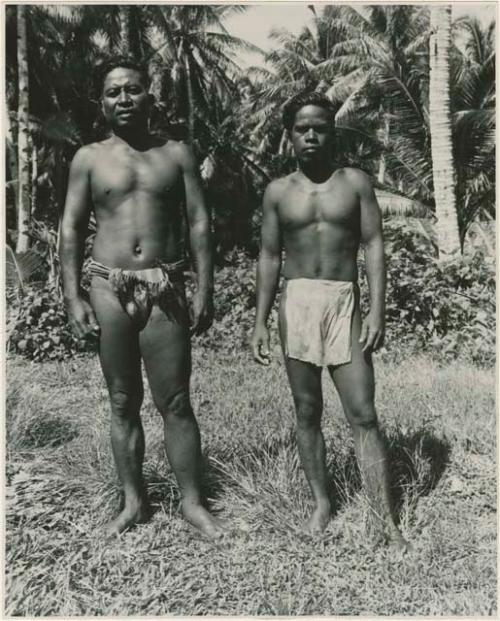 Two men standing, with palms in background