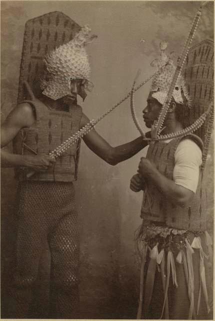 Two men with porcupine fish helmets, coconut fiber armor and taumangaria