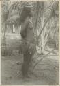 Woman standing in front of palm, side view