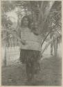 Woman holding baby in a sling and standing in front of palm