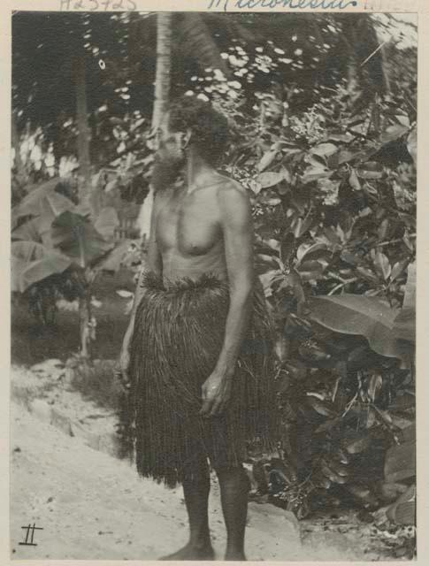 Man standing in front of trees, side view