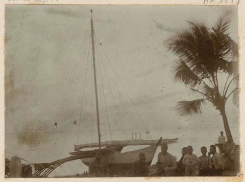 People on shore in front of outrigger canoe