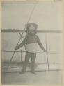 Man with taumangaria, coconut fiber armor and porcupine fish helmet standing on deck of boat