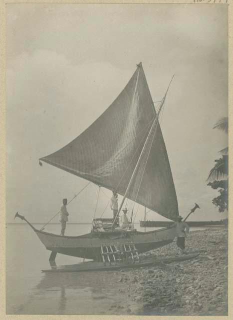 People and outrigger canoe on beach