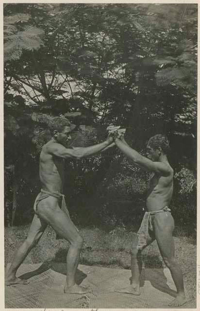 Men hand wrestling on mat