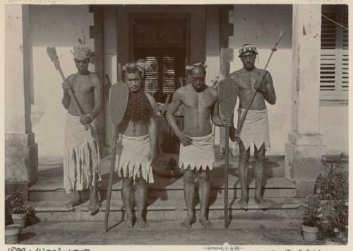 Four men holding paddles and clubs