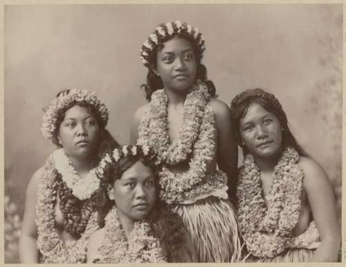 Four young women in grass skirts and leis