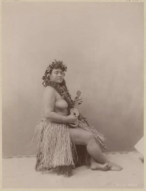 Studio portrait of woman in grass skirt with ukulele