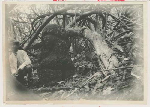 Man sitting by a carved stone figure