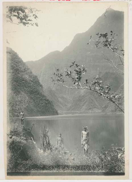 Three boys standing by a lake