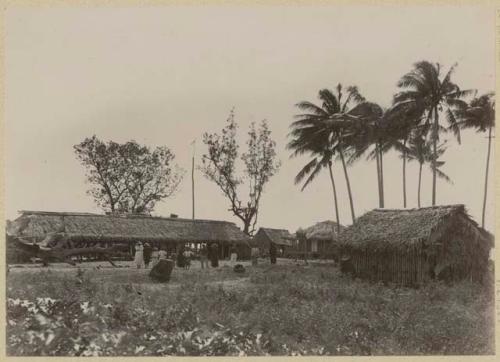 Group of people in front of long thatched structure