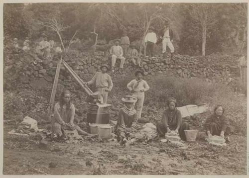 Women washing, men and dog in background