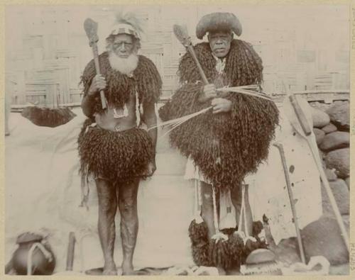 Two men with clubs dressed in garments made of human hair