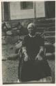 Woman sitting in front of structure with stone foundation