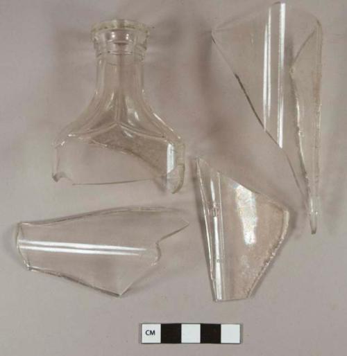 Molded colorless bottle glass fragments; embossed with hash marks and numbers up the sides; one is rim fragment, with stove pipe finish