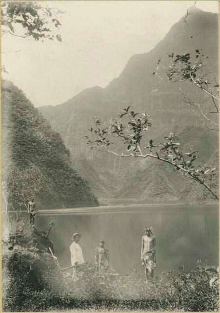 Three men, one in Western dress, in front of lake