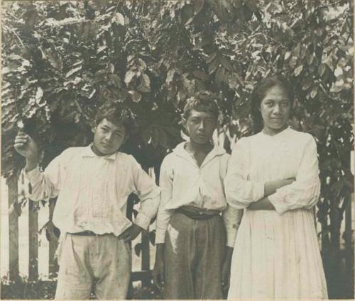 Two boys and a girl in front of fence