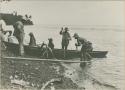 Men in canoe on shoreline