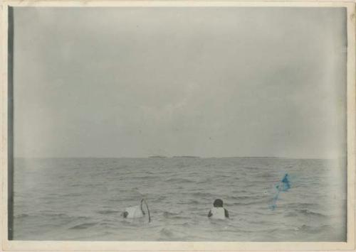 Two pearl divers in water with net