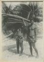 Two men, one carrying woven palm fronds