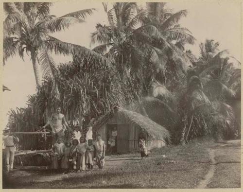 Men, women, and children outside small building