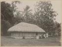 Women and children outside bamboo building