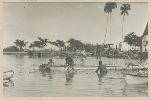 Men and boy in canoe net fishing