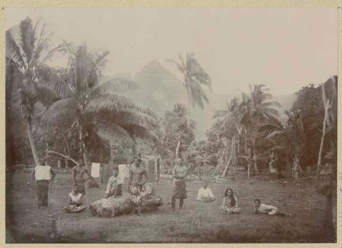 Men, woman, and child in clearing with drying laundry