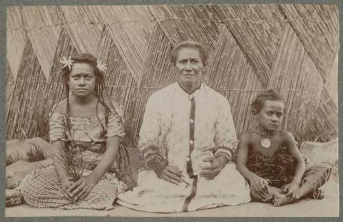 Older woman, younger woman, and child in front of bamboo wall