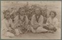 Girls seated on mat in front of foliage